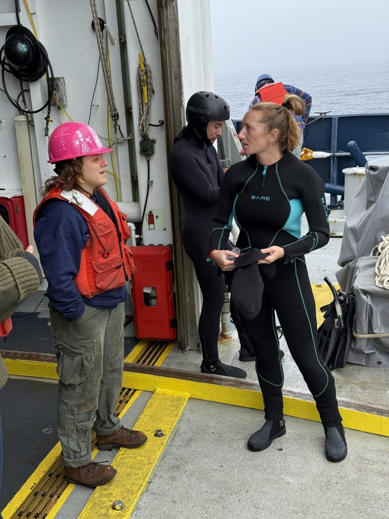 Svømmerne Molly Smith og Wren Sakai gjør seg klare til utsettingen av Alvin. Her sammen med Alvin-besetningsmedlem og pilot under opplæring Molly Pike (JC).